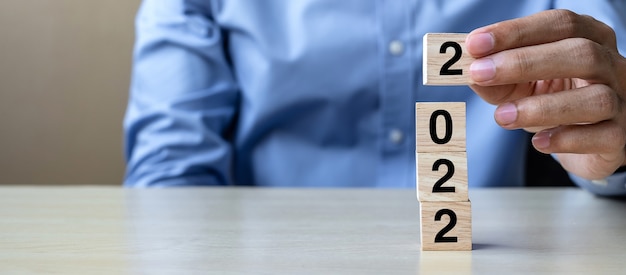 hand holding wooden cube blocks with 2022 text on table 