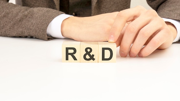 Hand holding wooden cube blocks with text r and d research and development on white table background marketing concepts