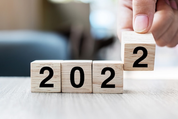 손을 잡고 블록 2021 ~ 2022 텍스트 위에 뒤집힌 나무 큐브