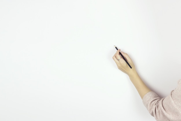 Hand holding wooden pencil starting to draw on Blank White Wall, Copy space.