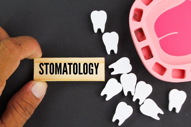 stomaology라고 적힌 나무 명판을 들고 있는 손.