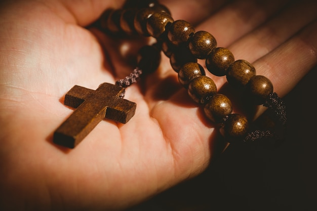 Hand holding wooden rosary beads