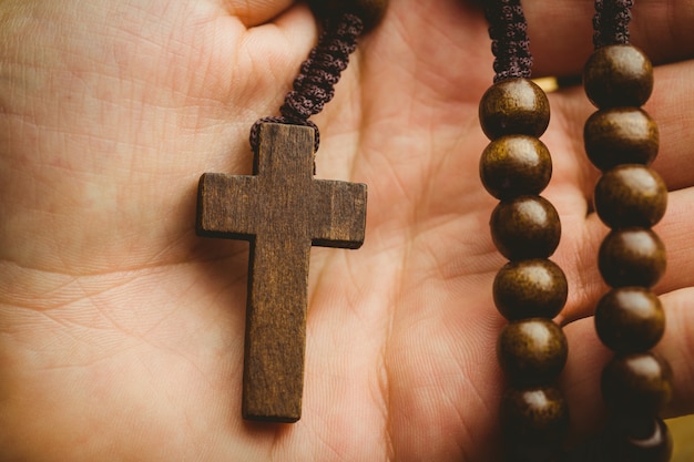 Hand holding wooden rosary beads