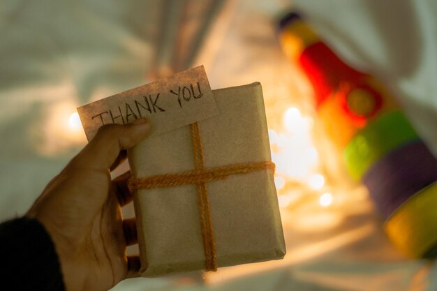 Photo hand holding a wrapped gift box and a note 