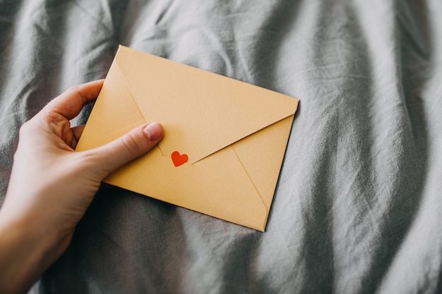 hand holding a yellow envelope with a heart on it