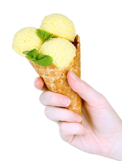 Рука держит желтое мороженое с мятой в вафельном рожке, изолированном на белом