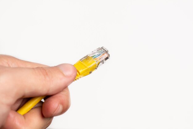 Hand holding yellow internet LAN cable on white background.