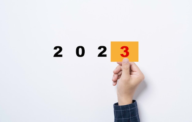 2022年から2023年のコンセプトの新しい事業年度の準備のための3番目の黄色い紙を持っている手。