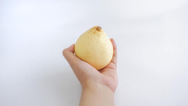 Hand holding yellow pear isolated on white background