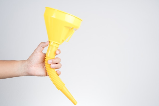 Photo hand holding yellow plastic funnel cone for water or fluid transfer