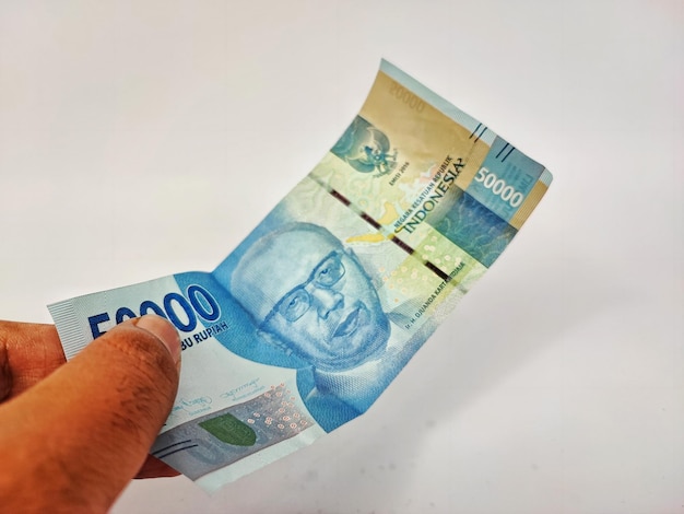 A hand holds a 100000 peso bill.