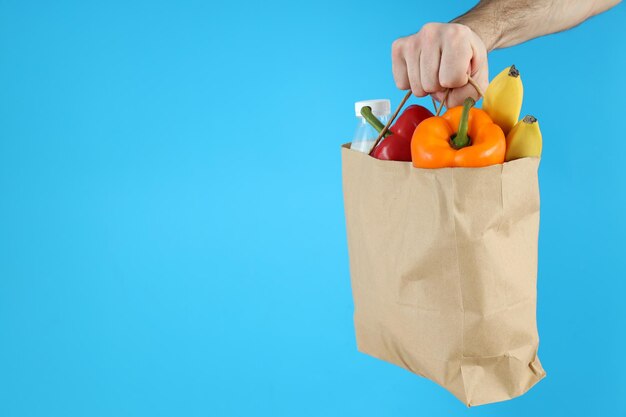 Hand holds bag with food on blue background