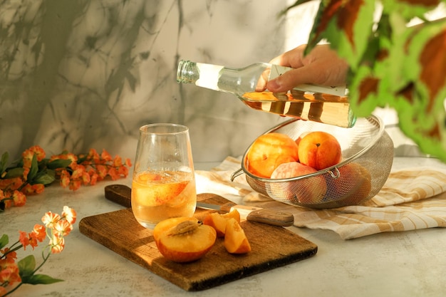 Hand holds a bottle to pour lemonade into a glass with ice and fruit Cold drink summer cocktail