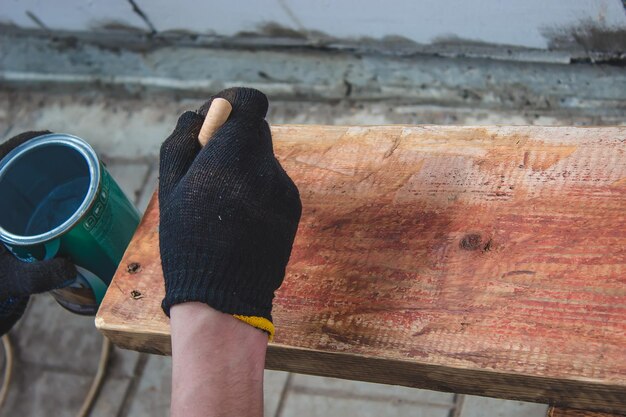 Hand holds a brush apply varnish paint on the board board painting