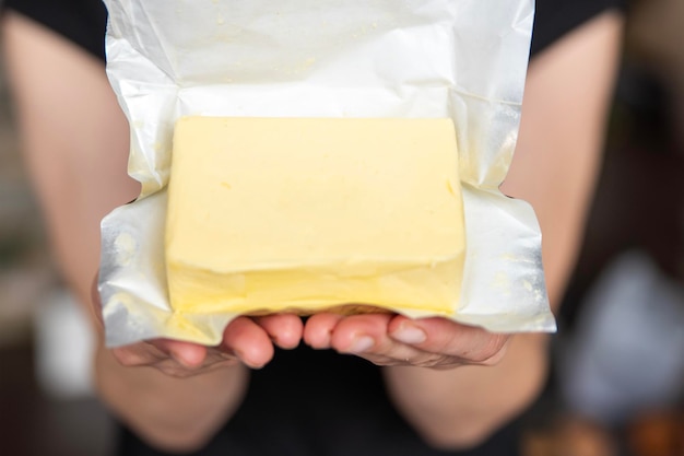 A hand holds butter in a pack closeup process of making sandwiches with butter