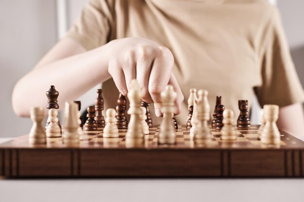 Hand holds chess piece and makes a move Faceless boy develops game strategy selective focus on hand