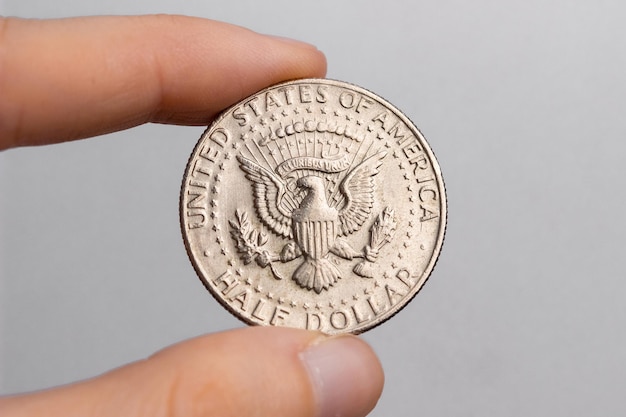 Photo a hand holds a coin of 50 american cents on a white background close-up.