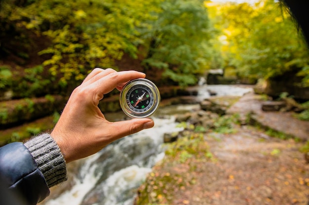 Hand holds a compass on the background of the river