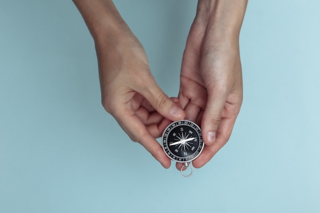 hand holds a compass on blue background. navigation, adventure concept