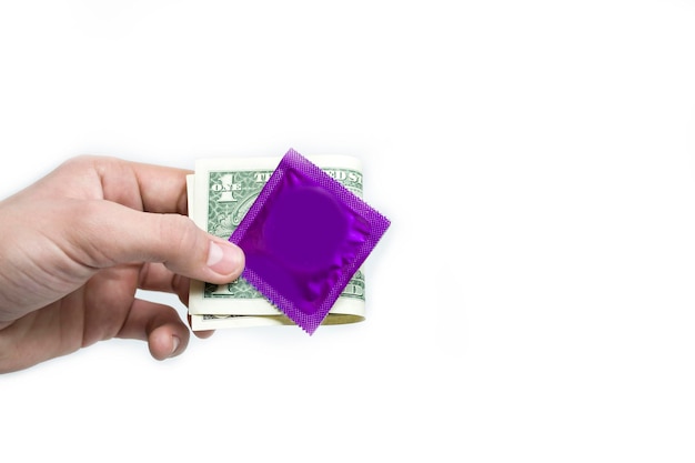 The hand holds a condom in and a dollar on a white background