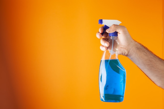 Hand holds detergent on orange background