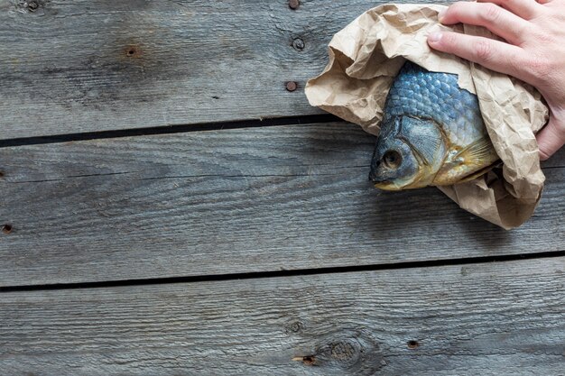 Photo hand holds dried volga bream vobla in a crumpled kraft paper roll, delicious beer snack