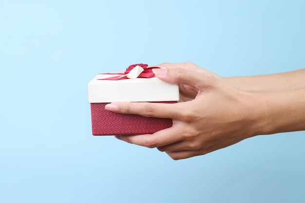 Руки держат подарочную коробку, изолированную на синем фоне