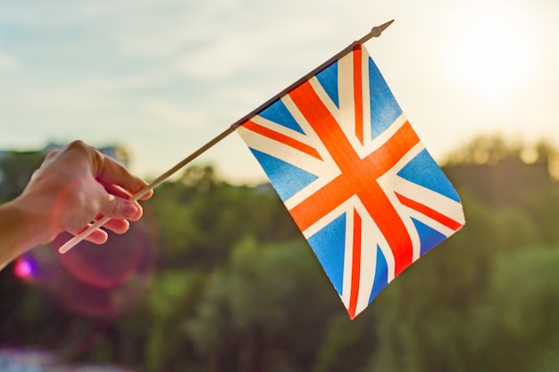 Hand holds Great Britainin flag an open window