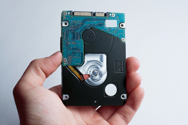 A hand holds hard disk drive against the white background