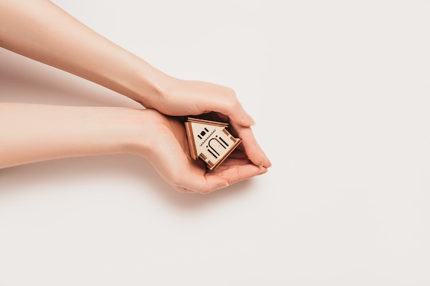Hand holds house miniature model on white background. Investment, real estate, home, housing
