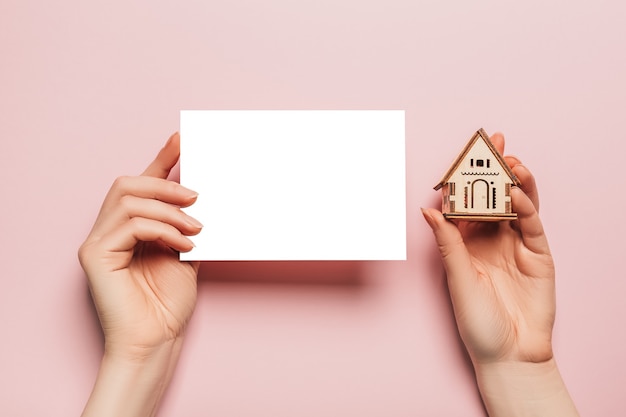 Photo hand holds house miniature model with blank space on a pink space