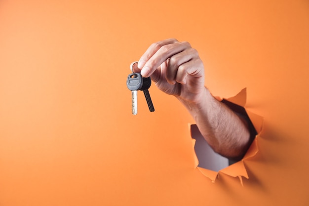 Hand holds a key on an orange background