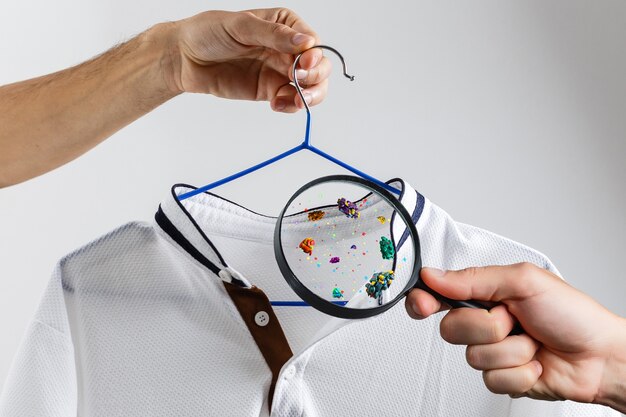 Photo hand holds a magnifier, bacteria on clothes