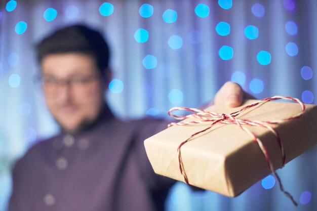 Photo hand holds a new year gift on the background of a garland