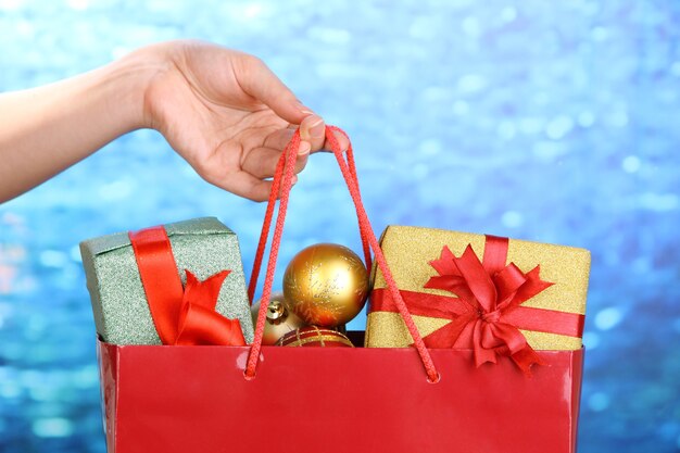 Hand holds package with christmas balls and gifts