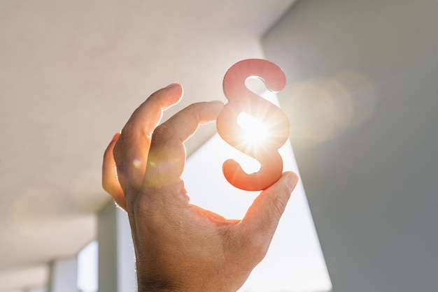 Hand holds paragraph symbol in the sun  at a office building