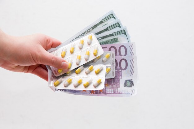 hand holds pills and bills