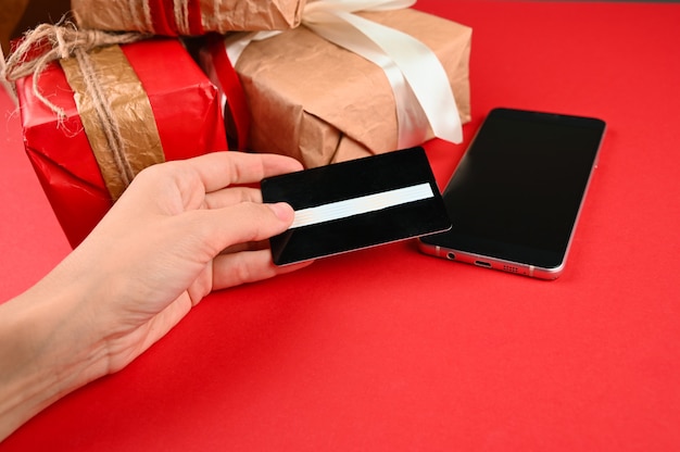 Hand holds a plastic card on the background of gifts. High quality photo