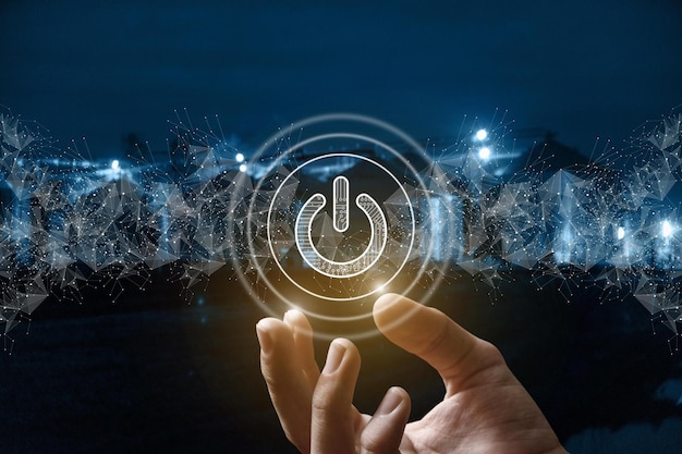 a hand holds a power button in the air with a blurry background.
