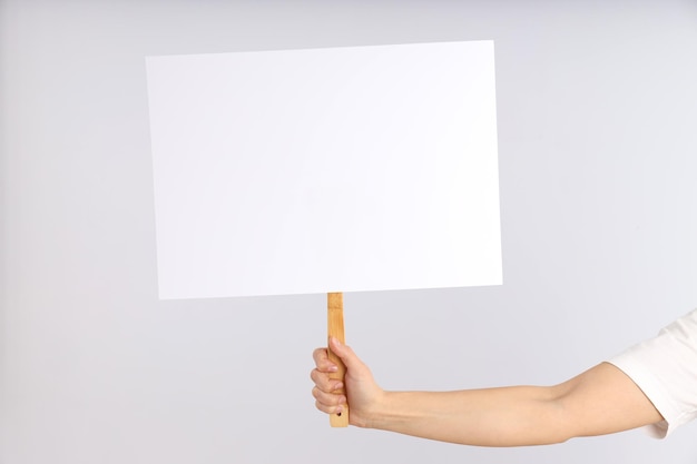 Hand holds protest sign on light background