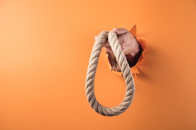 Hand holds rope on orange background