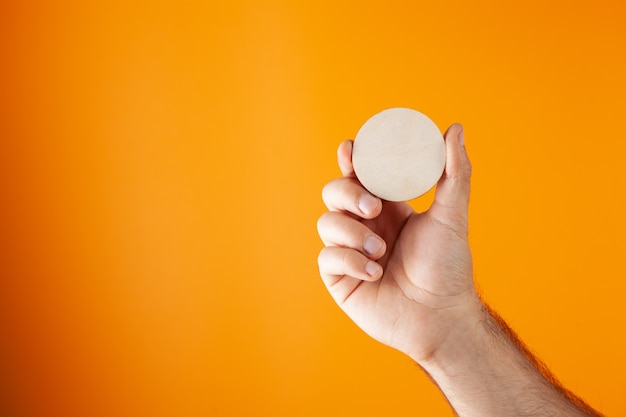 Hand holds round background on orange background