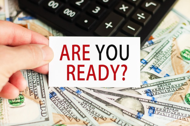 A hand holds a sign with the inscription - banknotes and a calculator on the table. Finance and economics concept.