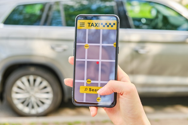 Hand holds smartphone and finger clicks on taxi search button in application.