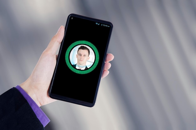 Hand holds a smartphone with face identification