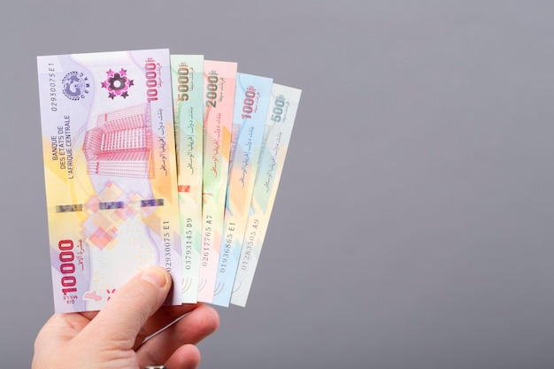 A hand holds a stack of 100, 000 banknotes.