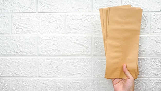 Hand holds stack of envelopes on a white wall