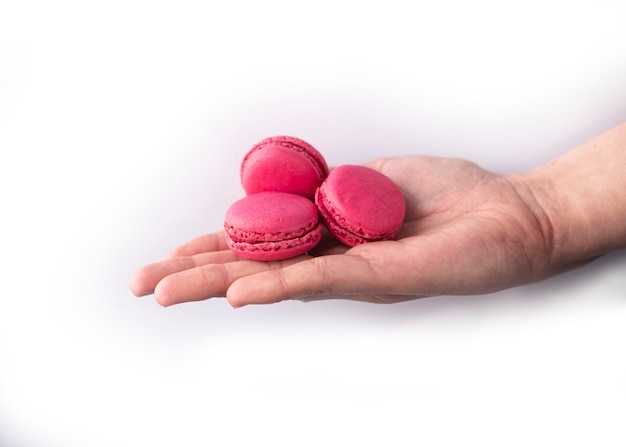 A hand holds three macaroons on a white background.