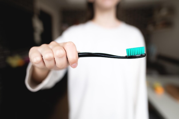 Hand tiene uno spazzolino da denti in primo piano su uno sfondo bianco della sua giacca lo sfondo è sfocato