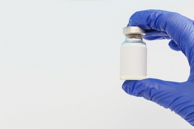 Hand holds Vaccine glass bottle